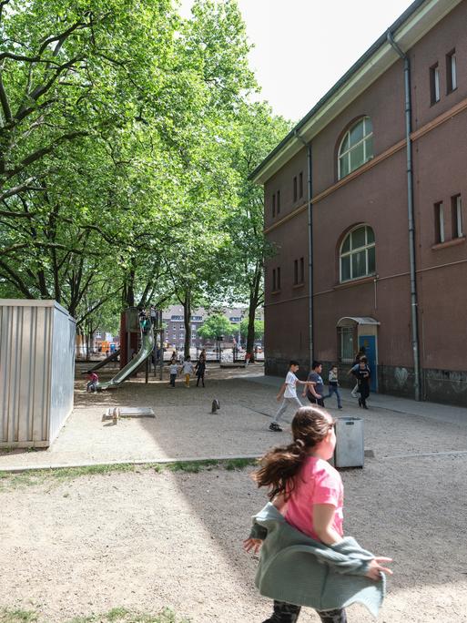 Auf dem Schulhof der Grundschule GGS am Hochfelder Markt in Duisburg spielen Kinder an einem Klettergerüst.