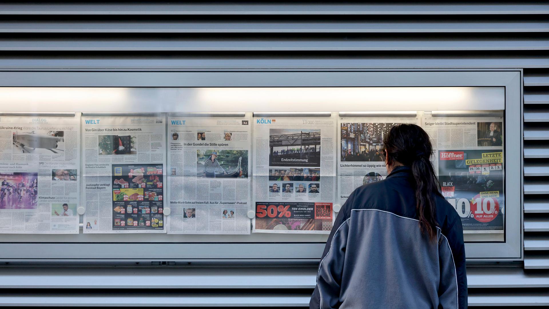 Ein Leser studiert die Schlagzeilen am Aushangkasten der Kölnischen Rundschau. (Themenbild, Symbolbild) Köln, 02.12.2024