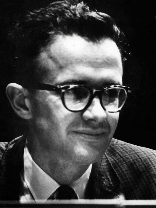 Ein Mann mit Brille und Krawatte blickt seitlich an der Kamera vorbei