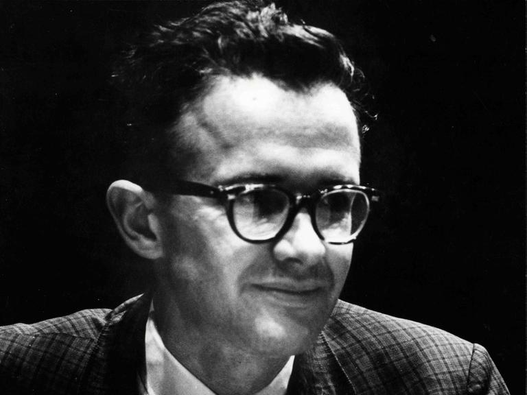 Ein Mann mit Brille und Krawatte blickt seitlich an der Kamera vorbei