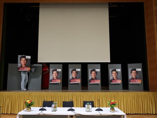 Auf einer Bühne hängen mehrere Wahlplakate mit dem Porträt von Sahra Wagenknecht.