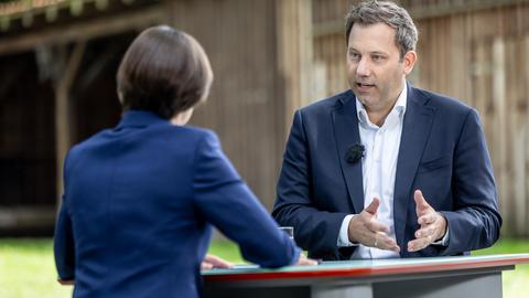 Klingbeil spricht zu ZDF Haupstadtkorrespondentin Diana Zimmermann, die mit dem Rücken zur Kamera sitzt. 