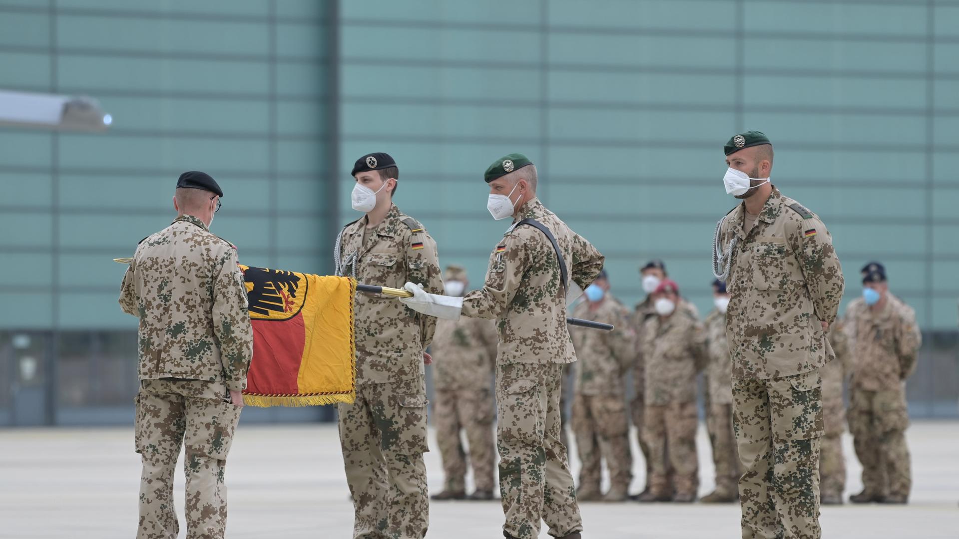 Brigadegeneral Ansgar Meyer (l), der letzte Befehlshaber der Bundeswehr in Afghanistan, rollt vor dem Transportflugzeug vom Typ Airbus A400M der Luftwaffe mit anderen Bundeswehrsoldaten die Truppenfahne ein. 