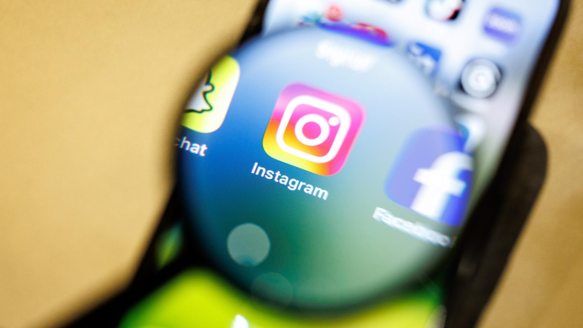 Das Logo der App Instagram ist am 29.12.2024 durch eine Lupe auf dem Display von einem Smartphone zu sehen. Instagram ist ein soziales Netzwerk mit Fokus auf Video- und Foto-Sharing, das vom Unternehmen Meta Platforms betrieben wird.