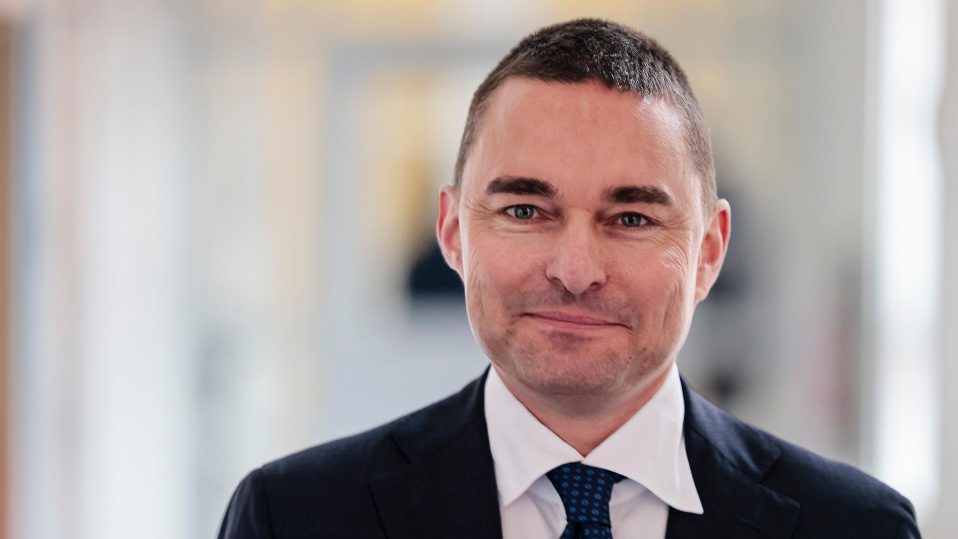 Eine Porträt-Aufnahme von Lars Windhorst. Er trägt einen dunklen Anzug und eine dunkle Krawatte und blickt etwas lächelnd in die Kamera. Eine Porträt-Aufnahme von Lars Windhorst. Er trägt einen dunklen Anzug und eine dunkle Krawatte und blickt etwas lächelnd in die Kamera.