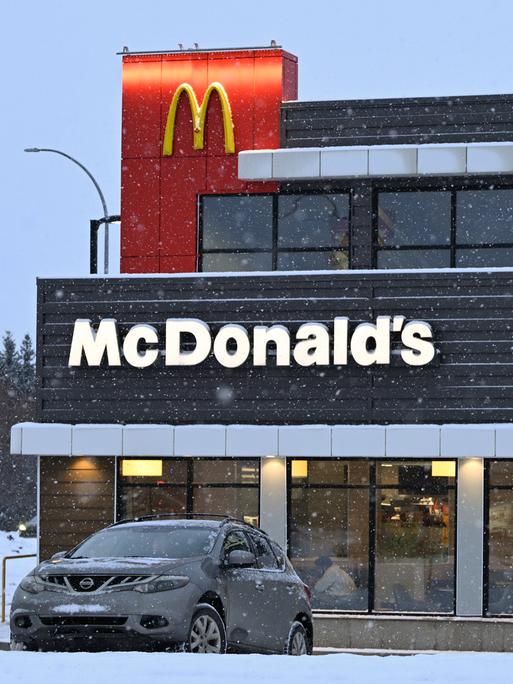 McDonald's Restaurant in South Edmonton in den USA. Vor dem Lokal parkt ein Auto in einer verschneiten Straße. 