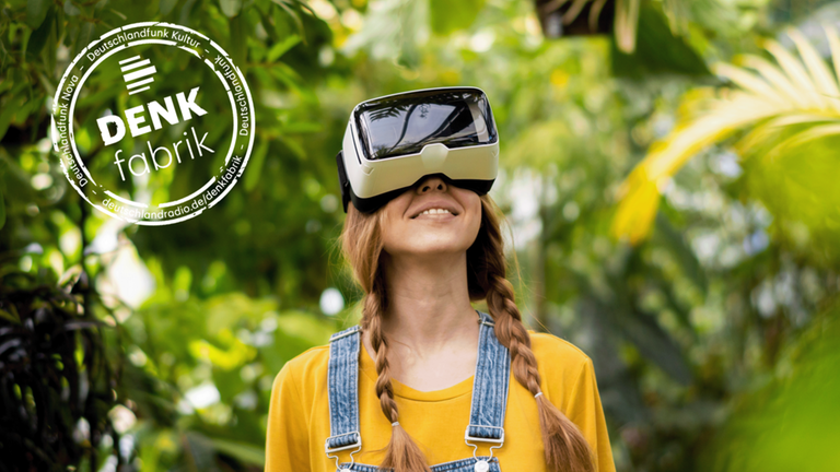 Eine junge Frau vor grüner Umgebung blickt mit VR-Brille nach oben