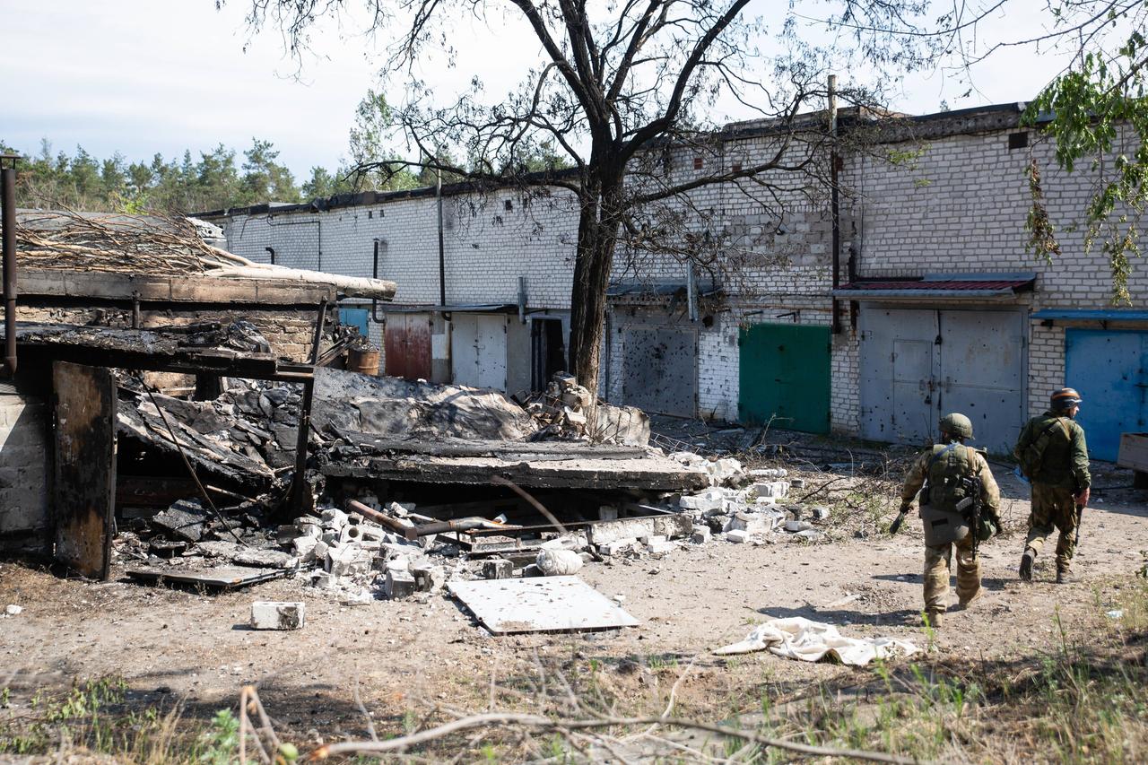 Soldaten gehen an einem völlig zerstörten Gebäude in der Region Luhansk in der Ukraine vorbei.
