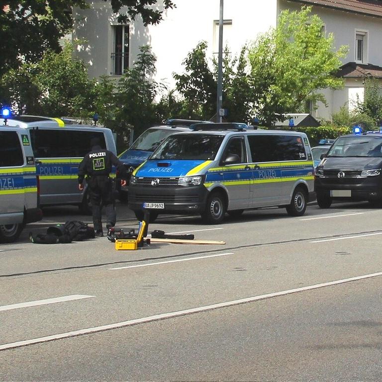 Polizisten sind im Einsatz bei einer mutmaßlichen Geiselnahme in einer Bankfiliale in Regensburg. Das Bild zeigt mehrere Mannschaftswagen und Polizisten davor.