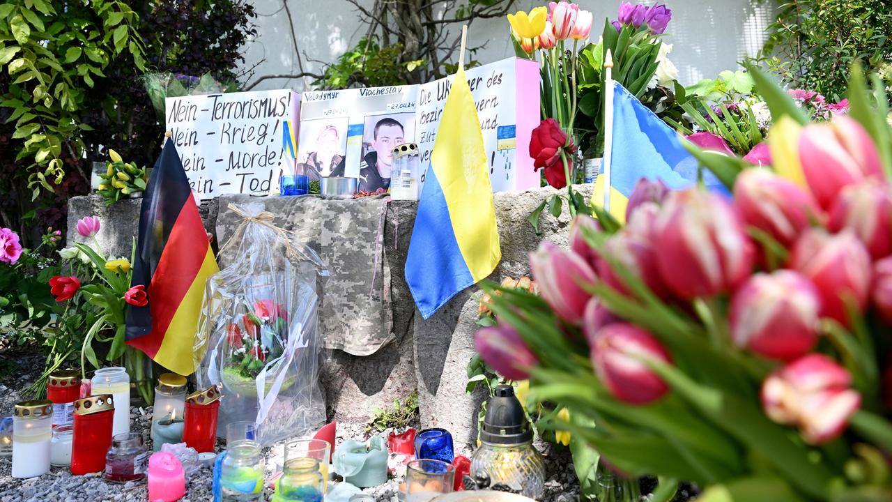 Blumen, Kerzen und Plakate liegen neben Fotos von zwei getöteten Ukrainern im bayrischen Murnau.