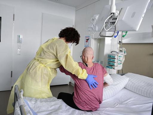 Eine Pflegerin in eine eine Patientin in ihrem Krankenbett auf. 