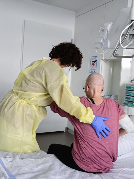 Eine Pflegerin in eine eine Patientin in ihrem Krankenbett auf. 