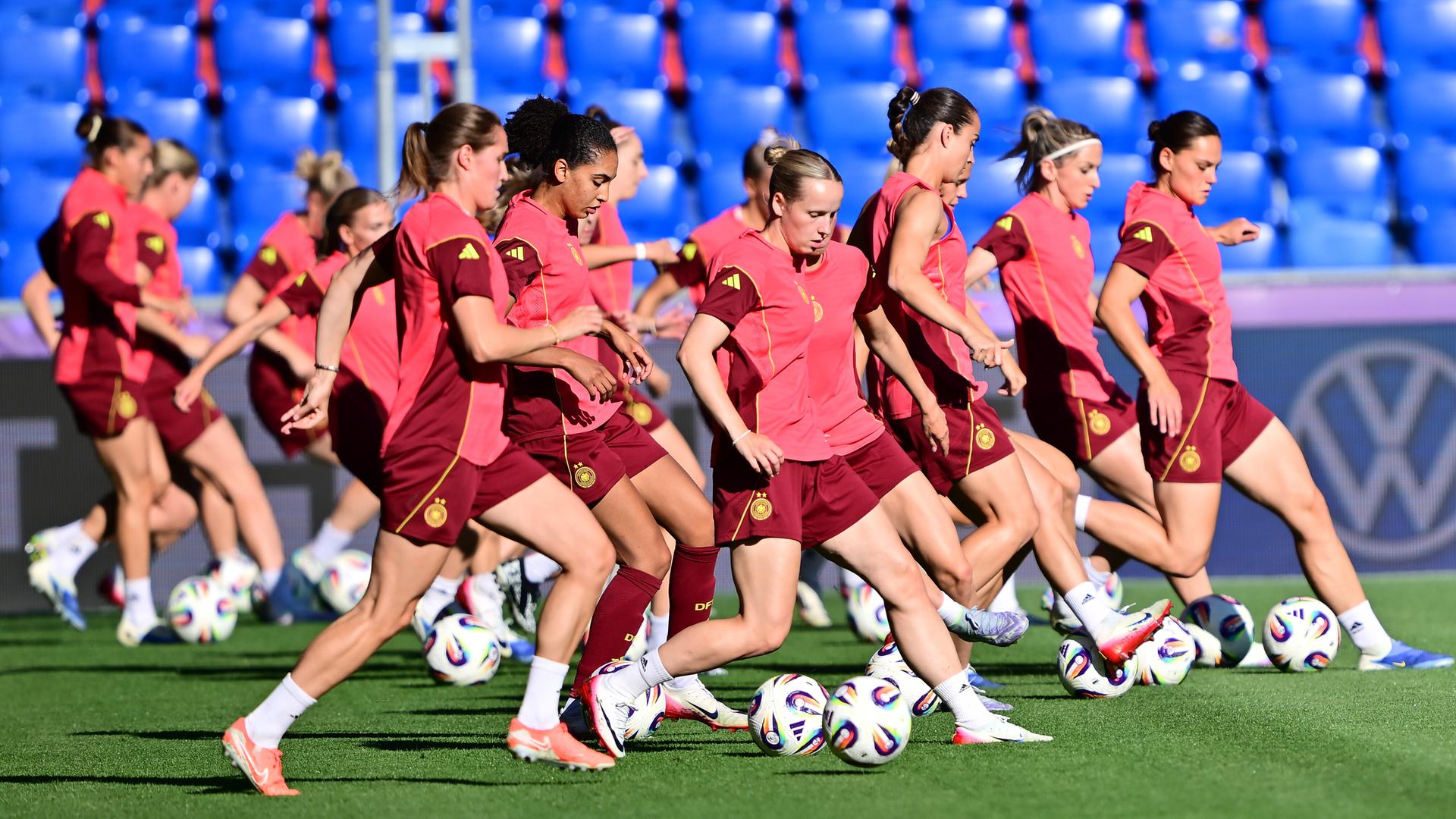 Die deutschen Fußballerinnen trainieren auf dem Platz. Sie tragen rote Trikots.