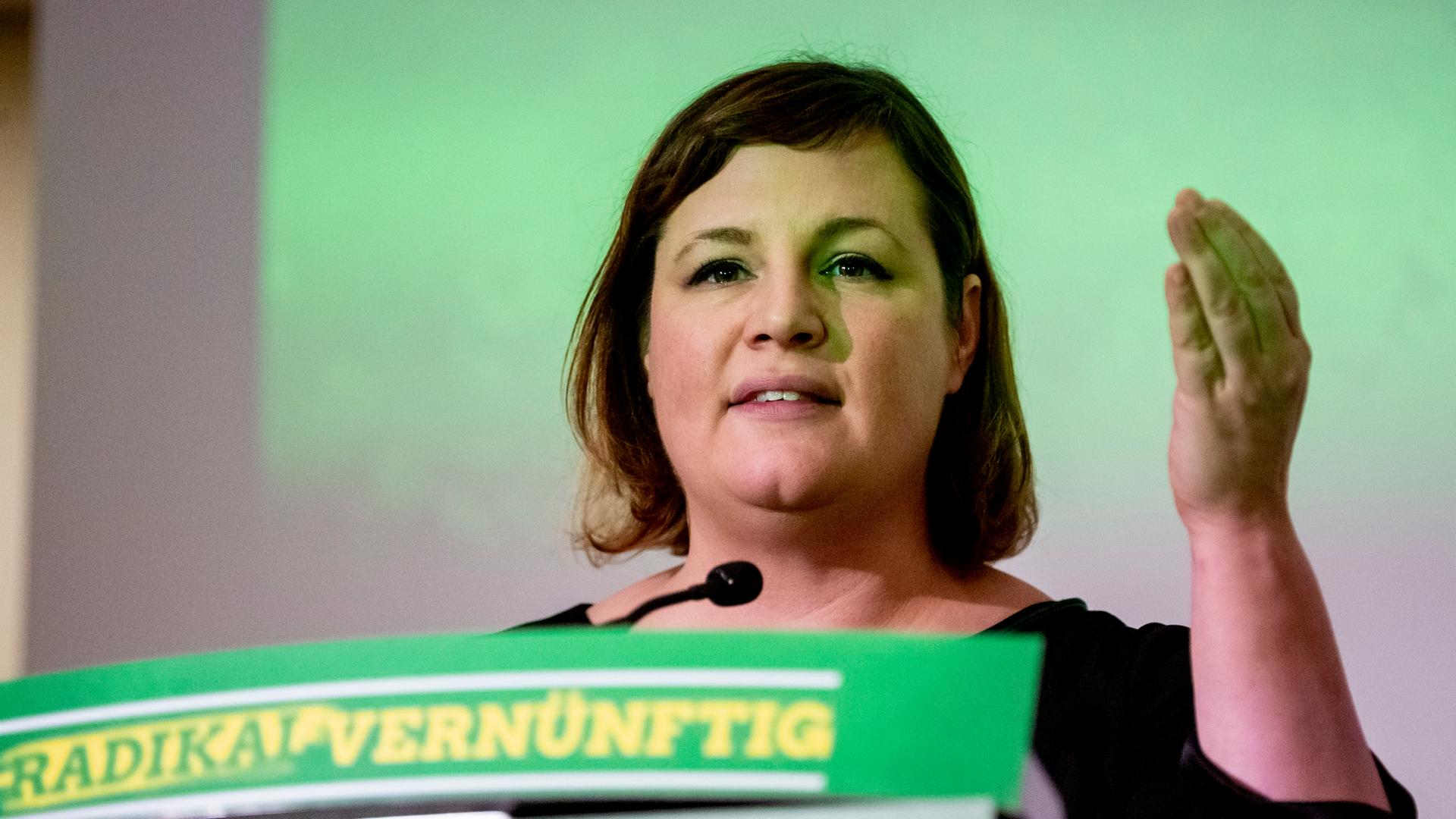 Antje Kapek spricht und gestikuliert mit ihrer linken Hand. Sie hat dunkle Haare, trägt ein schwarzes Oberteil. Auf dem rednerpult des Parteitags steht das Motto "radikal vernünftig" Antje Kapek spricht und gestikuliert mit ihrer linken Hand. Sie hat dunkle Haare, trägt ein schwarzes Oberteil. Auf dem rednerpult des Parteitags steht das Motto "radikal vernünftig"