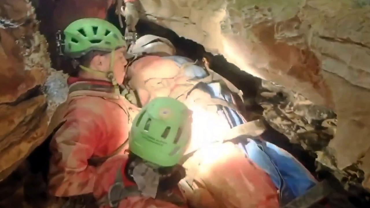 Zwei Retter halten in einem engen Gang die Trage mit der Forscherin darauf. Alle tragen Helme.