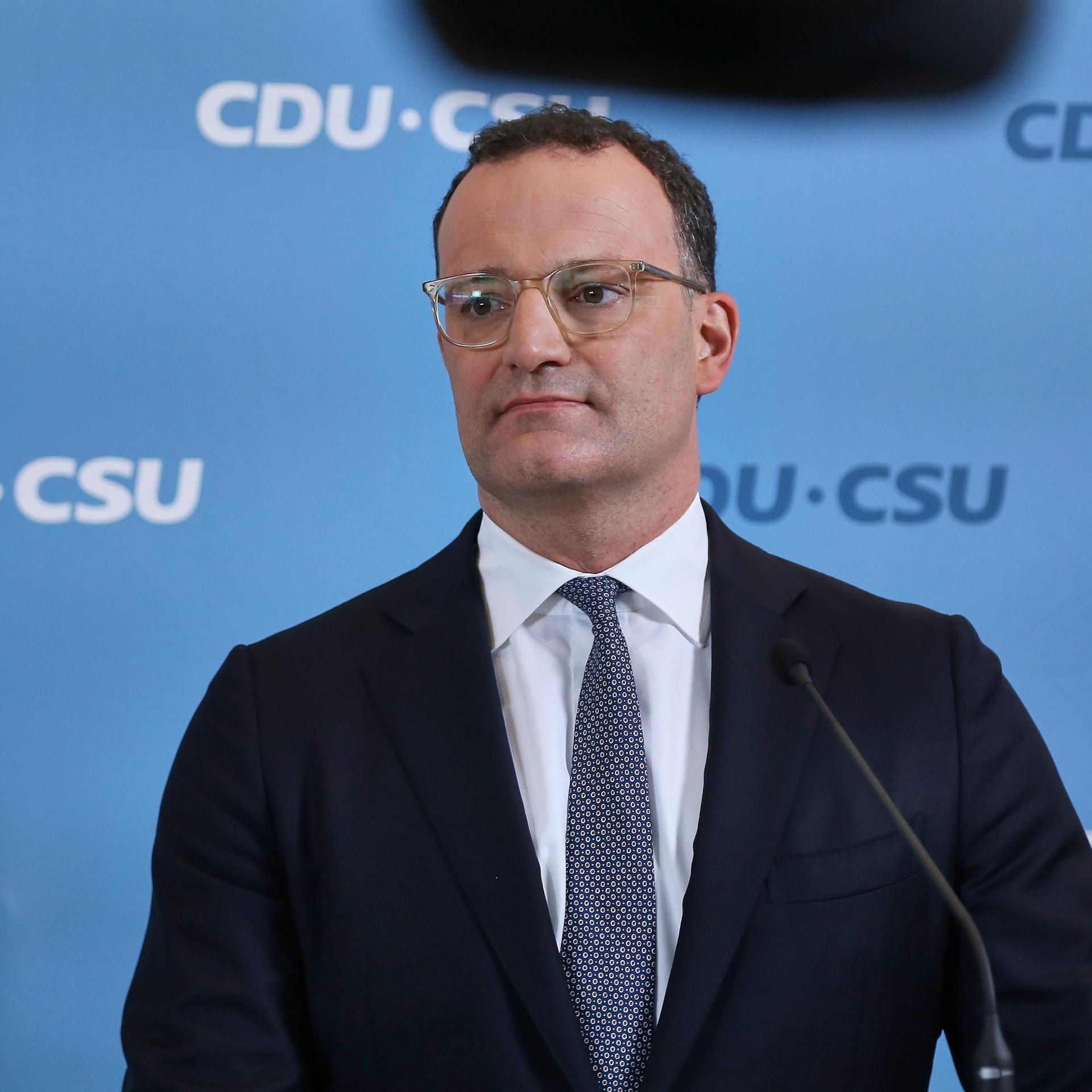 Jens Spahn steht vor einer Wand mit dem Logo der CDU/CSU-Bundestagsfraktion.