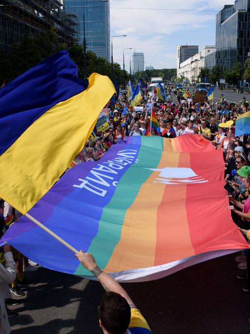 Menschen schwenken auf einer Parade in Warschau die Flagge der Ukraine