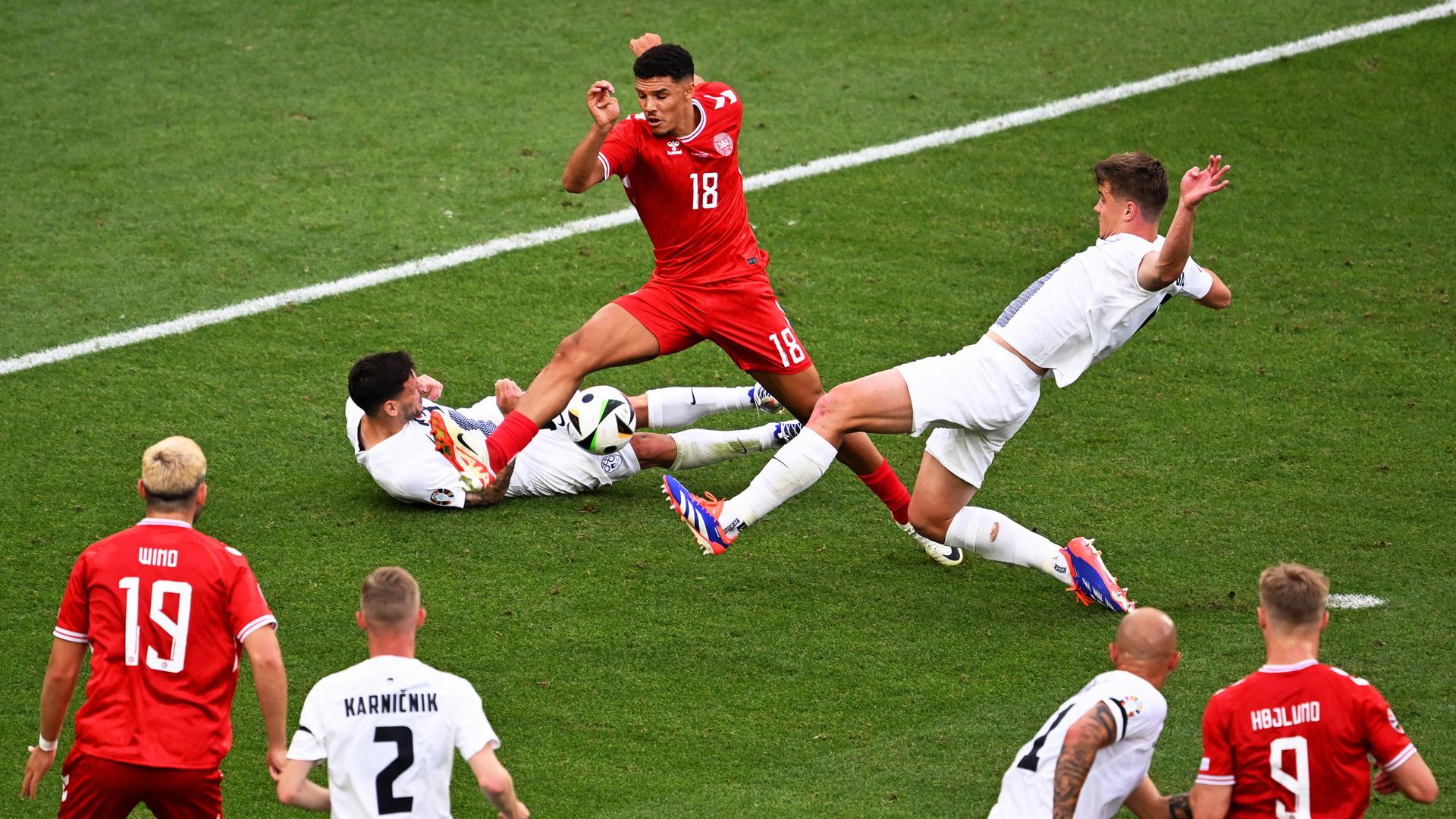 Fußball-Nationalspieler Dänemarks und Sloweniens kämpfen bei einem Spiel der Fußball-Europameisterschaft um den Ball. Fußball-Nationalspieler Dänemarks und Sloweniens kämpfen bei einem Spiel der Fußball-Europameisterschaft um den Ball.