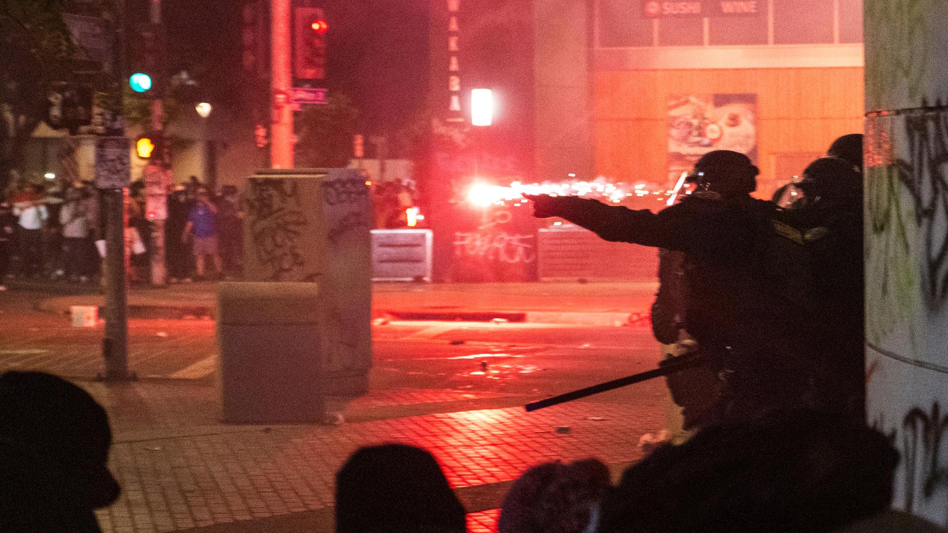 Polizisten gehen während der Proteste gegen die Razzien der Trump-Regierung gegen Einwanderer in Los Angeles vor Geschossen in Deckung. 