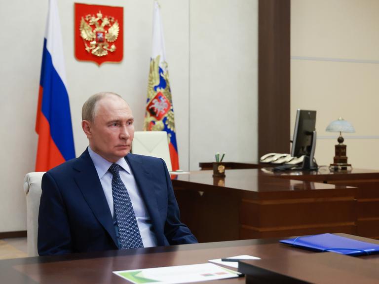 Russlands Präsident Wladimir Putin in seinem Büro mit der russischen Fahne im Hintergrund