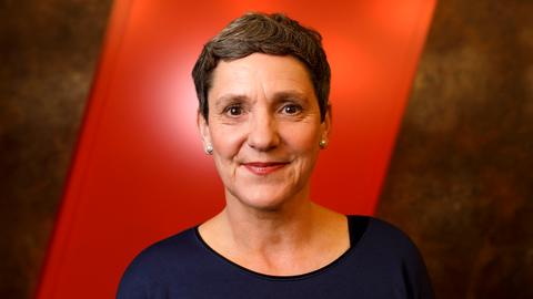 Felicitas Hoppe hat kurze, dunkle Haare. Im Hintergrund zieht sich ein roter Streifen schräg nach oben.