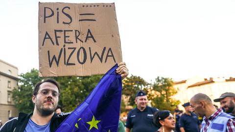 Ein Demonstrant hält in Krakau ein Banner hoch auf dem er gegen die Visa-Affäre protestiert sowie die Europafahne.  