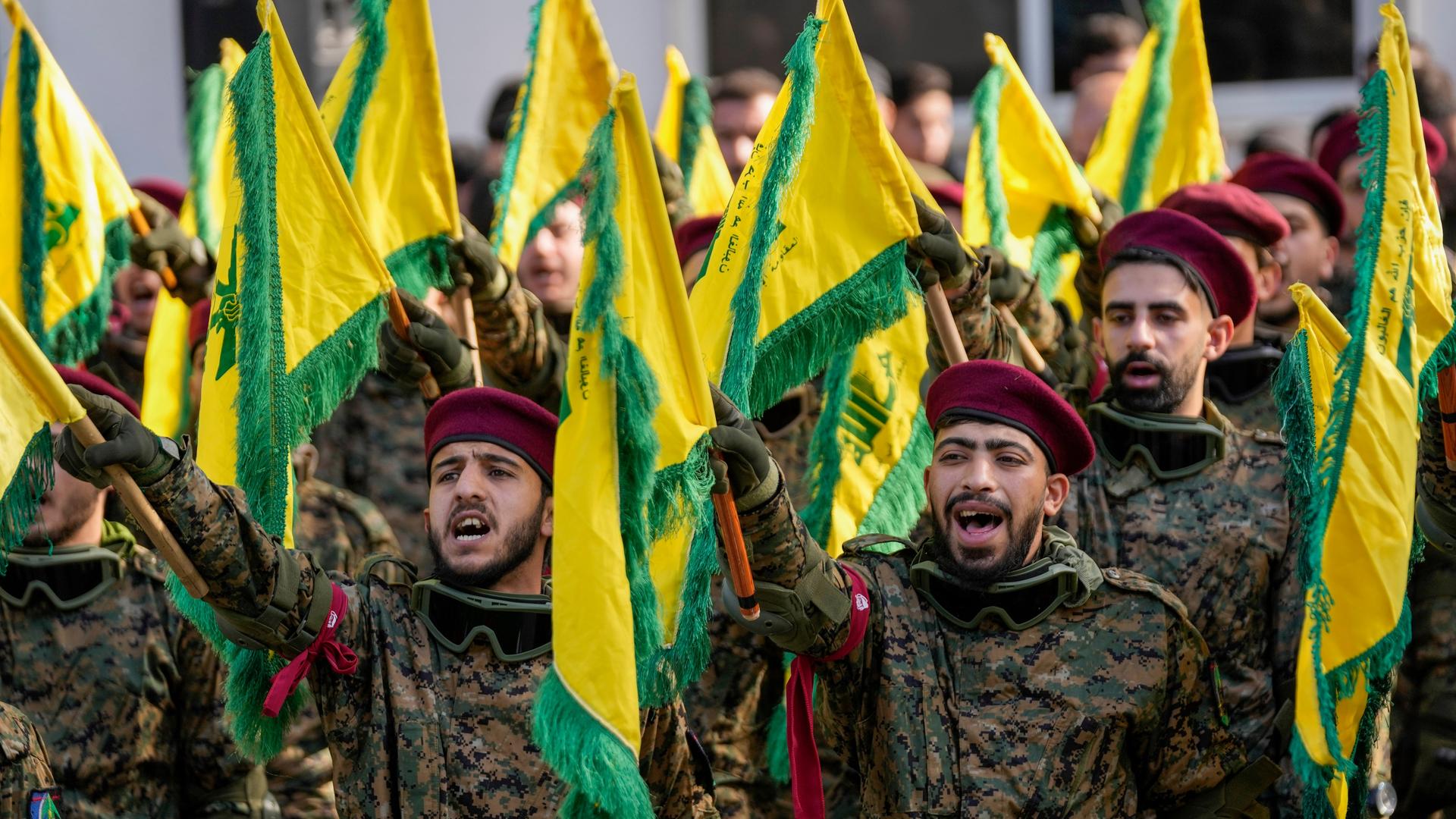 Libanon, Khirbet Selm: Hisbollah-Kämpfer halten Fahnen hoch bei der Beerdigung eines hochrangigen Hisbollah-Kommandeurs. 