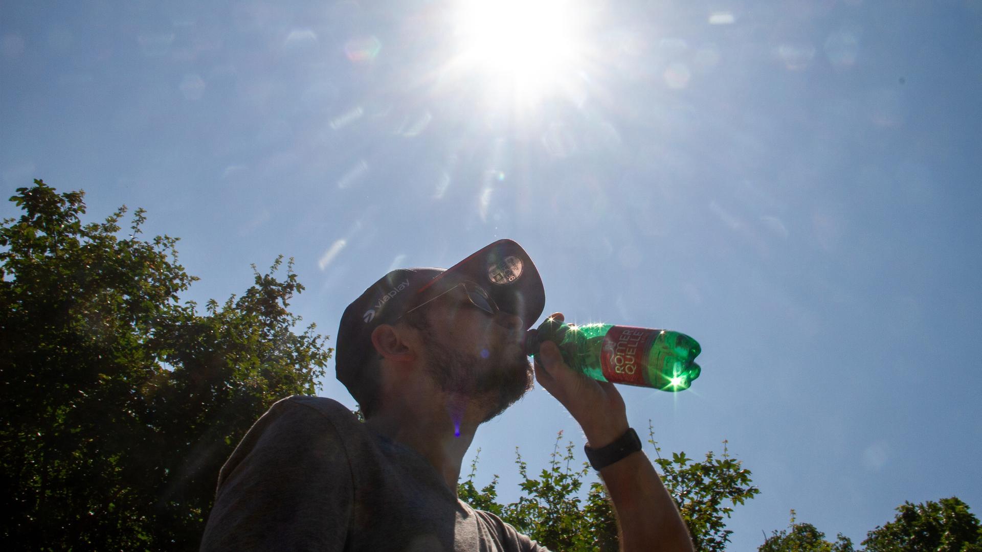 Silhouette eines Mannes mit einer Wasserflasche an einem heißen Sommertag