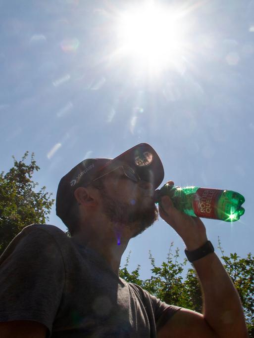 Silhouette eines Mannes mit einer Wasserflasche an einem heißen Sommertag