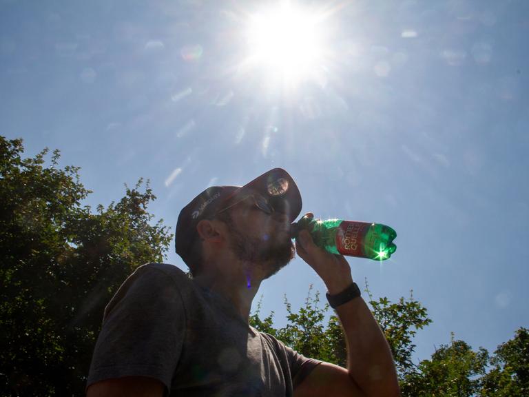 Silhouette eines Mannes mit einer Wasserflasche an einem heißen Sommertag