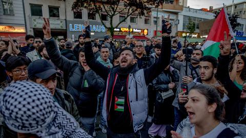 Demonstranten laufen durch eine Straße in Berlin. Eine Palästinenser-Flagge wird geschwenkt.
