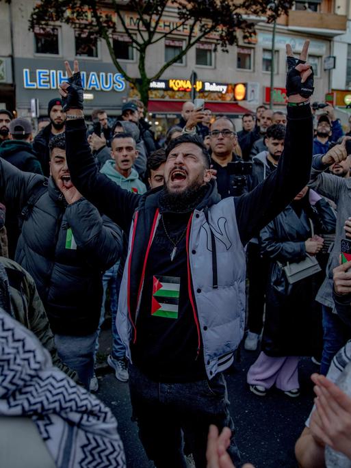 Demonstranten laufen durch eine Straße in Berlin. Eine Palästinenser-Flagge wird geschwenkt.