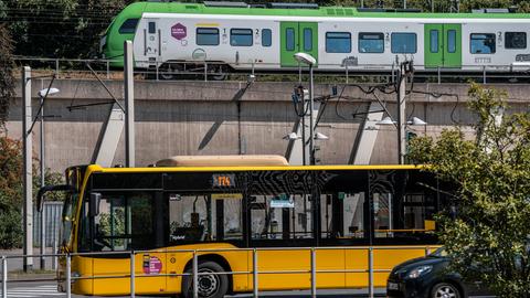 An einer ÖPNV Haltestelle in Essen in NRW steht ein gelber Bus und im Hintergrund eine grüne S-Bahn 