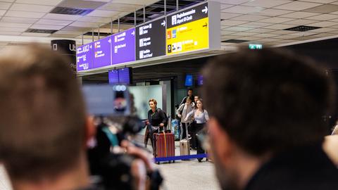 Menschen kommen aus dem Ankunftsbereich nach ihrer Ankunft am Frankfurter Flughafen.