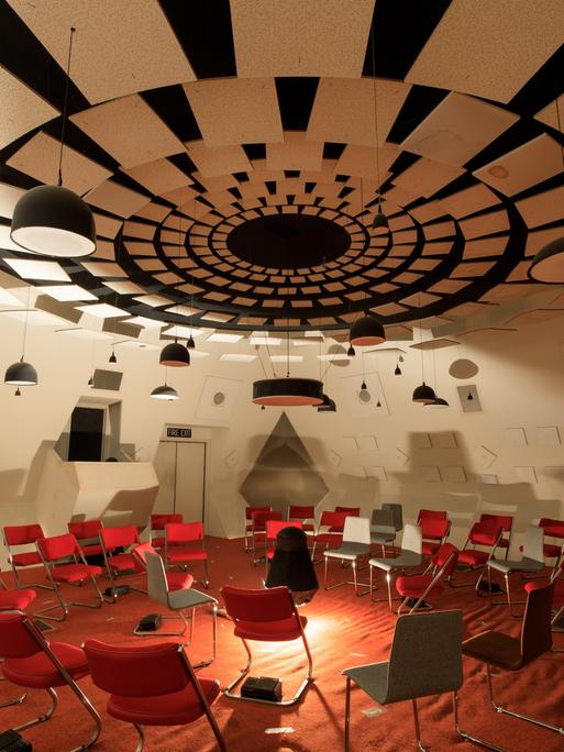 Ein futuristisch anmutender Raum in weiß mit roten Stühlen und den unterschiedlichsten hängenden, stehenden und verbauten Lautsprechern