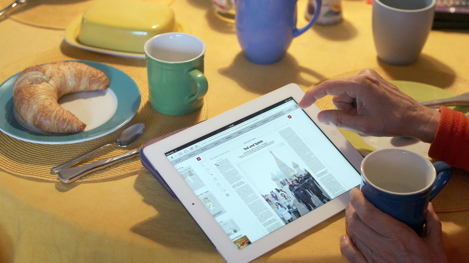 Eine Frau liest an einem Frühstückstisch eine E-Paper-Ausgabe der Süddeutschen Zeitung auf einem iPad. Eine Frau liest an einem Frühstückstisch eine E-Paper-Ausgabe der Süddeutschen Zeitung auf einem iPad.