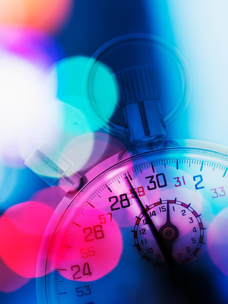 Eine Stoppuhr im Anschnitt, die leicht vor roten, blauen, violetten und pinken Lichtpunkten verschwindet