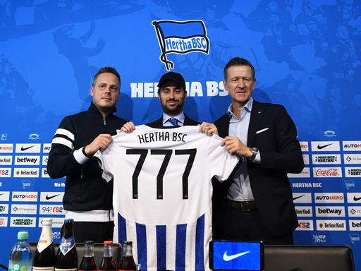 Kay Bernstein (r.), verstorbener Präsident von Hertha BSC, Josh Wander, Geschäftsfürher von 777 Partners und Hertha-Geschäftsführer Thomas E. Herrich halten ein Hertha-Trikot mit der Nummer 777 hoch.