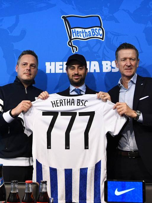 Kay Bernstein (r.), verstorbener Präsident von Hertha BSC, Josh Wander, Geschäftsfürher von 777 Partners und Hertha-Geschäftsführer Thomas E. Herrich halten ein Hertha-Trikot mit der Nummer 777 hoch.