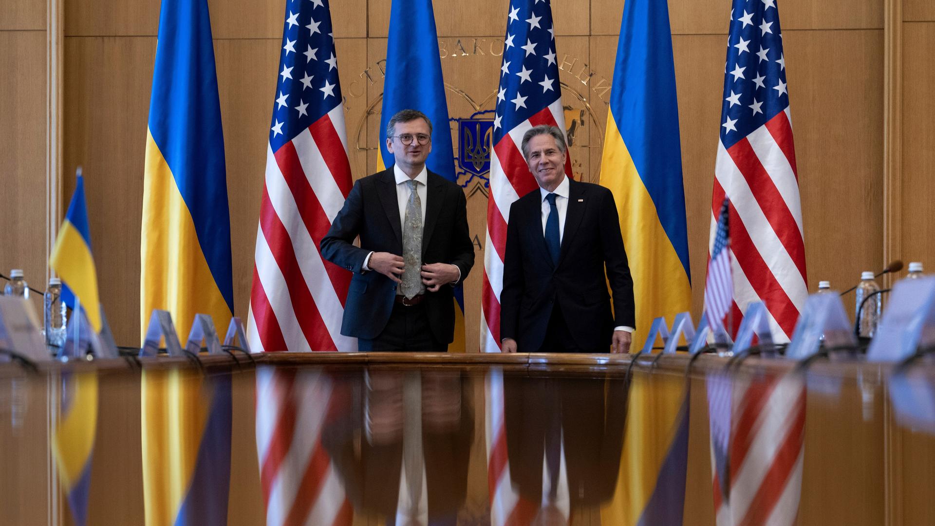 Der ukrainische Außenminister Dmytro Kuleba und US-Außenminister Antony Blinken posieren vor ihren Gesprächen für ein Foto. Hinter ihnen stehen ukrainische und US-amerikanische Fahnen. 