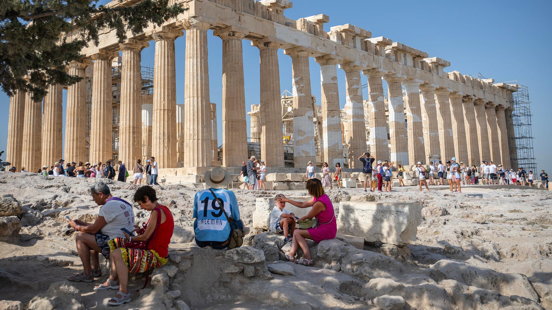 Touristen ruhen sich auf dem Akropolis-Hügel im Schatten aus. 