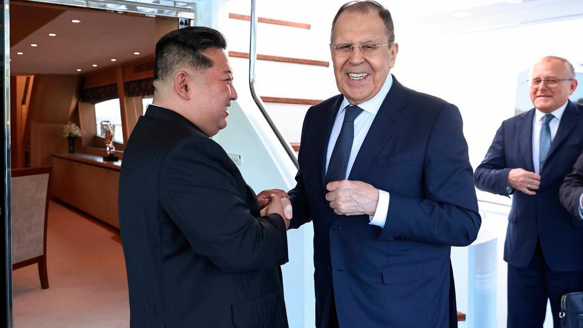 Kim hält mit beiden Händen die rechte Hand von Lawrow und lächelt ihn an, Lawrow blickt derweil in Richtung Kamera und lächelt.