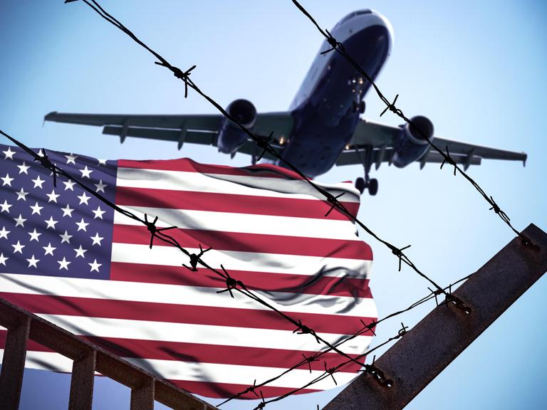Symbolbild mit einer Flagge der USA mit Stacheldraht und einem Flugzeug 