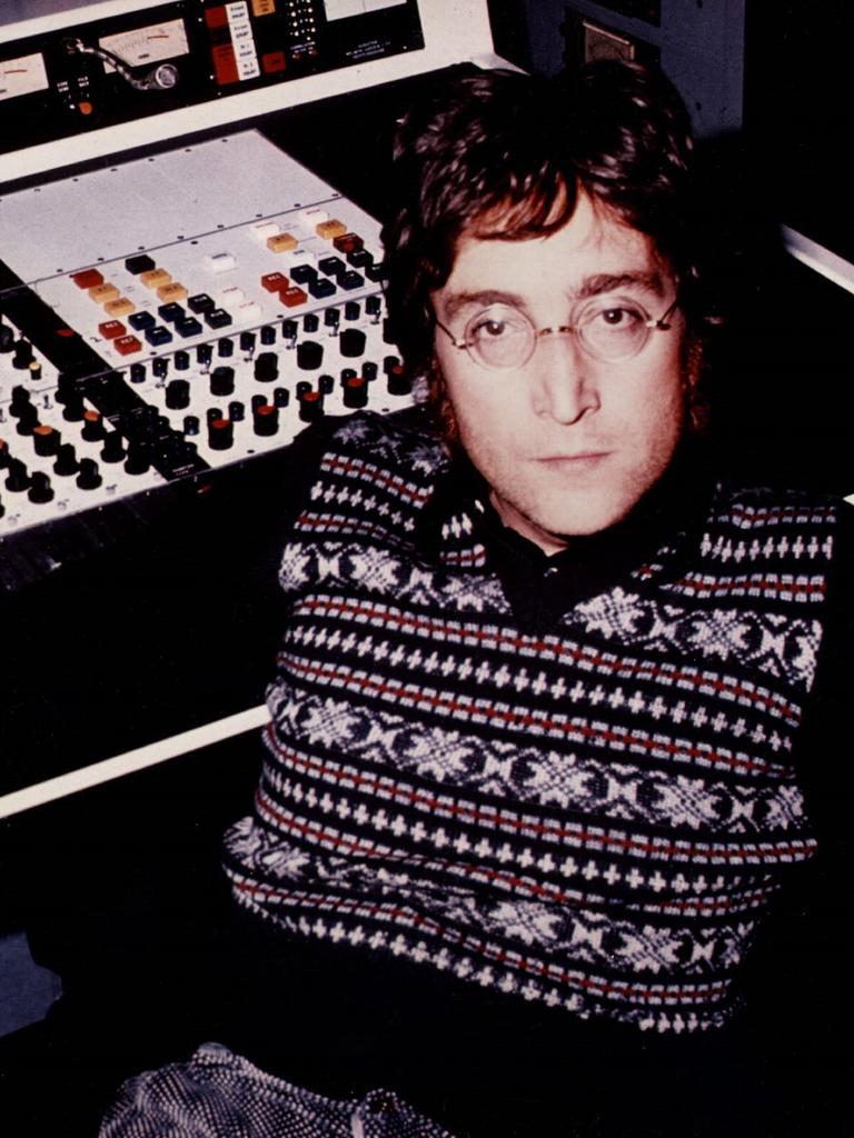 John Lennon sitzt an einer Studiokonsole aus den Siebzigern und blickt ernst in die Kamera