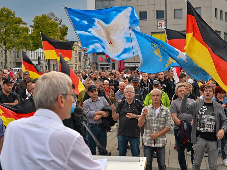 Hans-Christoph Berndt, Fraktionsvorsitzender der AfD im brandenburgischen Landtag, spricht auf der Demonstration von "Zukunft Heimat". Zu sehen sind Fahnen mit Friedenstaube und die Deutschlandfahne.