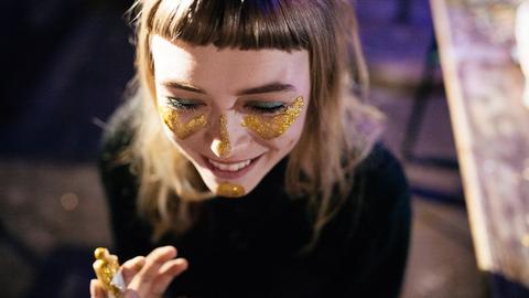 Eine junge Frau trägt goldenes Glitzer-Makeup im Gesicht