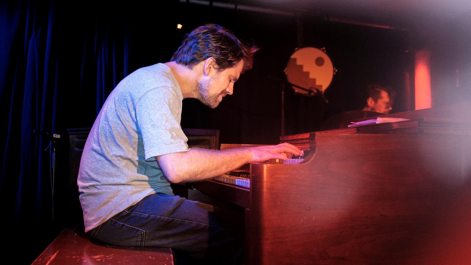 Kit Downes sitzt im grauen Shirt vertieft über einer Hammond-Orgel und spielt mit geschlossenen Augen auf einer Clubbühne.