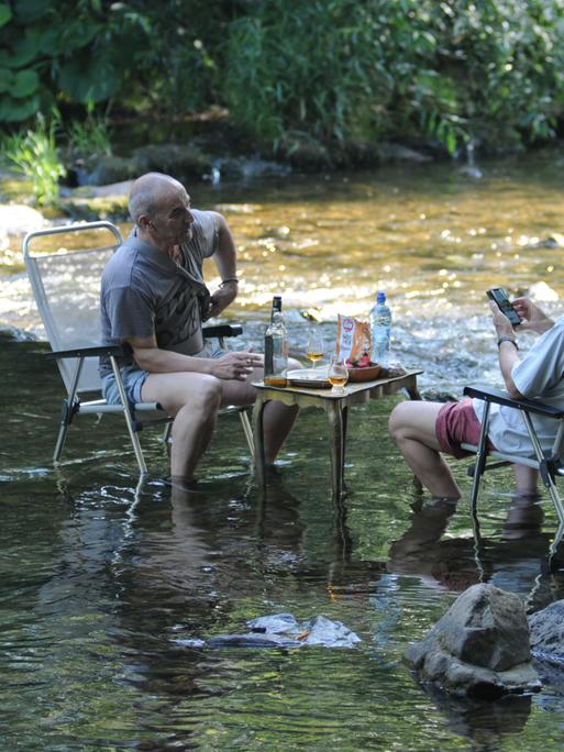 Bei heißen Temperaturen suchen Menschen am Ufer und im Flußes Dreisam in Freiburg im Breisgau.