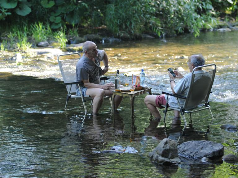 Bei heißen Temperaturen suchen Menschen am Ufer und im Flußes Dreisam in Freiburg im Breisgau.