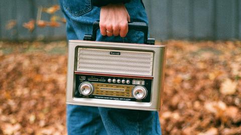 Ein Mensch hält ein portables Radiogerät in der Hand. 